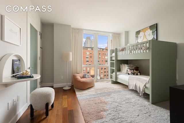 bedroom with baseboards, a city view, and wood finished floors