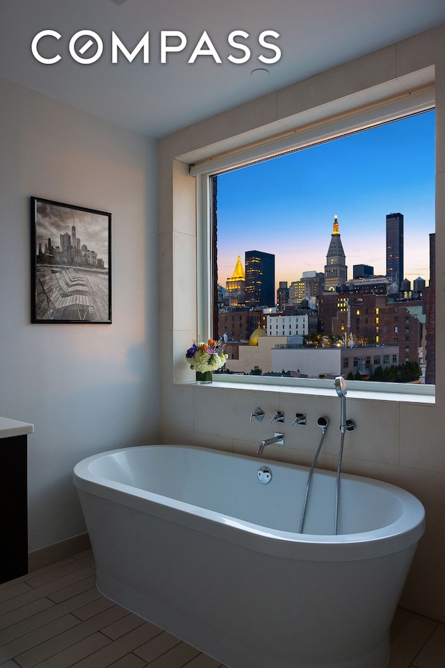 full bath featuring a freestanding tub and a city view