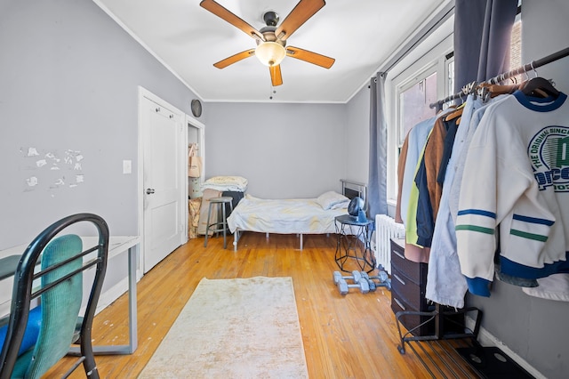 bedroom with crown molding, baseboards, a ceiling fan, and wood finished floors