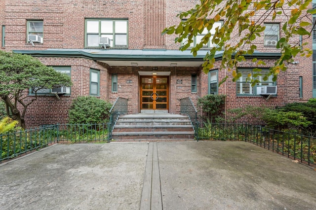 view of exterior entry with brick siding, french doors, and cooling unit