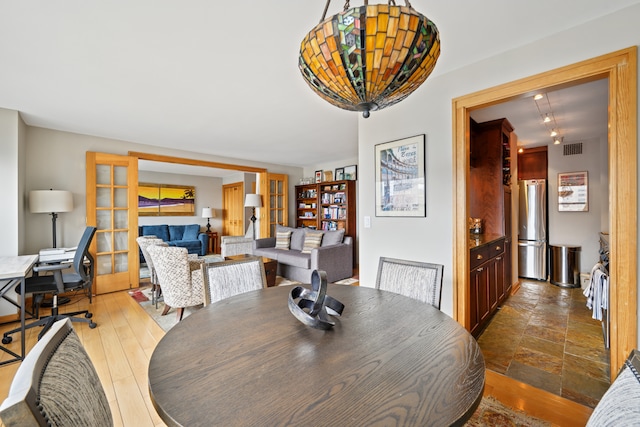 dining space featuring stone finish flooring, french doors, and visible vents