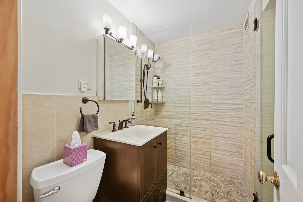 160 W End Ave Unit 24Gh, New York City, NY 10023 - bathroom featuring vanity, toilet, tile walls, and a shower stall