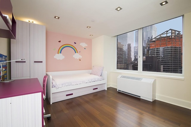 bedroom featuring heating unit, baseboards, and wood finished floors
