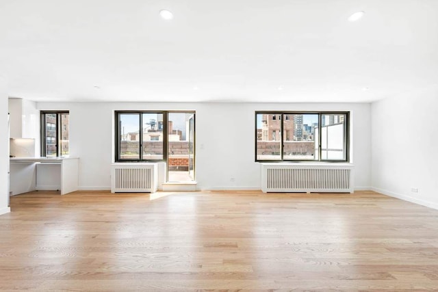 420 E 64th St Ephe, Ephe, New York City, NY 10065 - unfurnished living room featuring radiator heating unit, baseboards, and light wood-style flooring