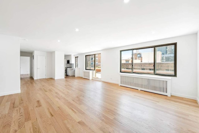 420 E 64th St Ephe, Ephe, New York City, NY 10065 - unfurnished living room featuring recessed lighting, baseboards, light wood-style flooring, and radiator heating unit
