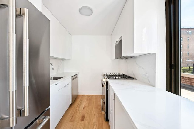 kitchen with a sink, white cabinets, stainless steel appliances, and light wood finished floors