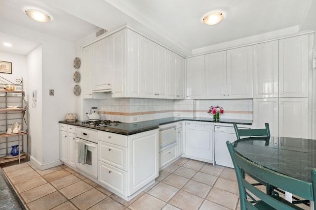 kitchen featuring white appliances, light tile patterned flooring, dark countertops, and tasteful backsplash