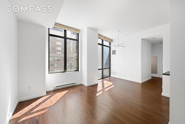 101 W 24th St Unit 5E, New York City, NY 10011 - empty room featuring a baseboard heating unit, wood-type flooring, a chandelier, and baseboards