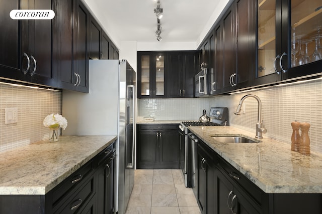 kitchen featuring backsplash, light stone countertops, appliances with stainless steel finishes, and a sink