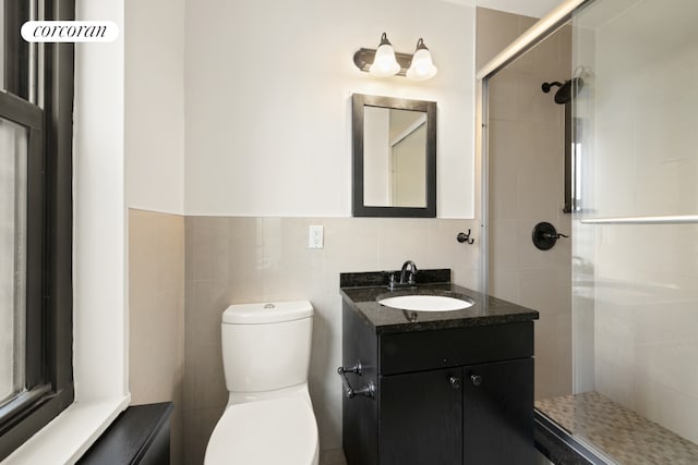 full bath with toilet, tile walls, a tile shower, and vanity