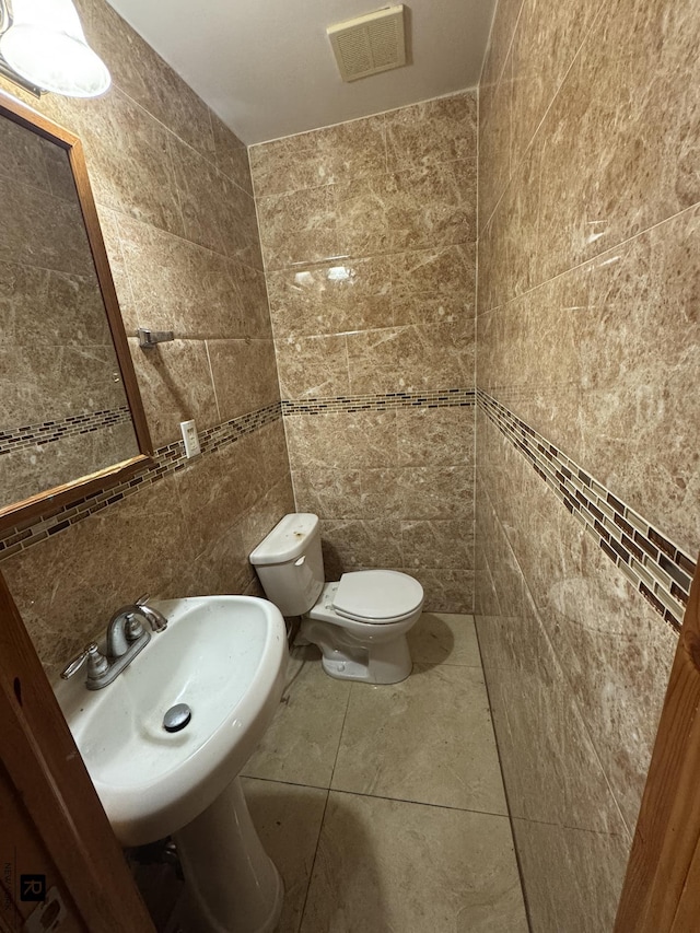 1264 E 73rd St, New York City, NY 11234 - bathroom featuring tile walls, toilet, a sink, and tile patterned floors