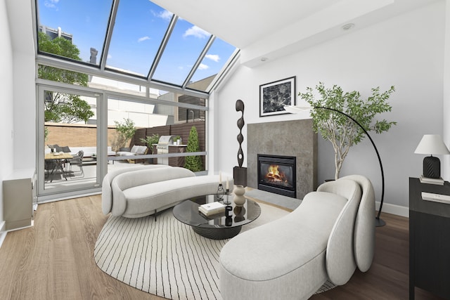 living area featuring baseboards, a glass covered fireplace, floor to ceiling windows, and wood finished floors