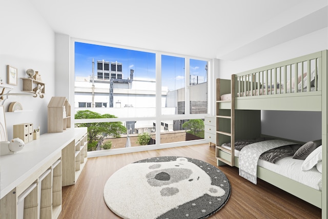 bedroom featuring a wall of windows and wood finished floors