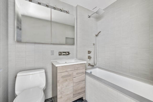full bath featuring toilet, tiled shower / bath, tile walls, and vanity