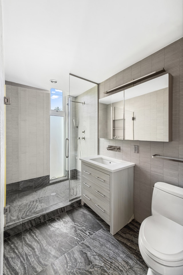 full bathroom with vanity, marble finish floor, toilet, tile walls, and a stall shower