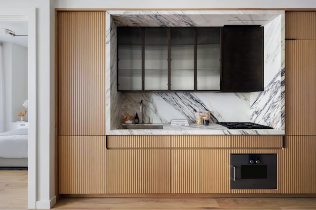 135 E 47th St Unit 20B, New York City, NY 10017 - kitchen featuring wood finished floors, a sink, and decorative backsplash
