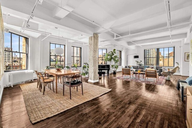 dining space featuring track lighting, radiator, wood finished floors, beamed ceiling, and baseboards