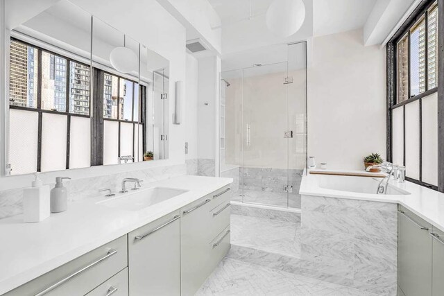 bathroom featuring vanity, visible vents, a bath, and a stall shower