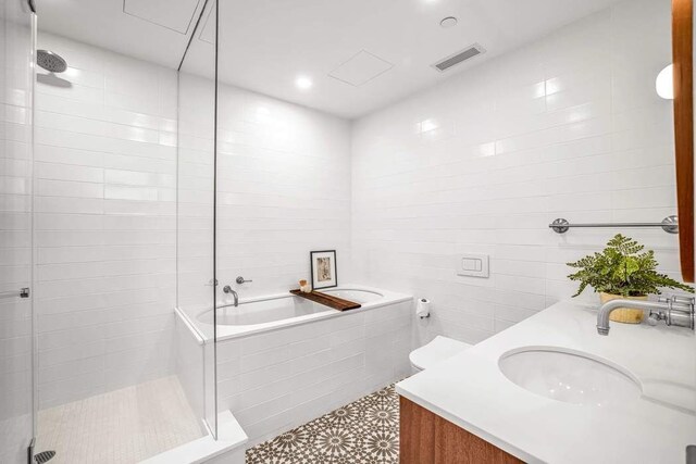 full bathroom featuring a garden tub, visible vents, tile walls, a shower stall, and vanity