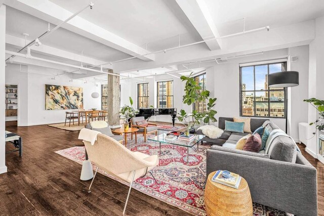 living room featuring baseboards, wood finished floors, and beam ceiling
