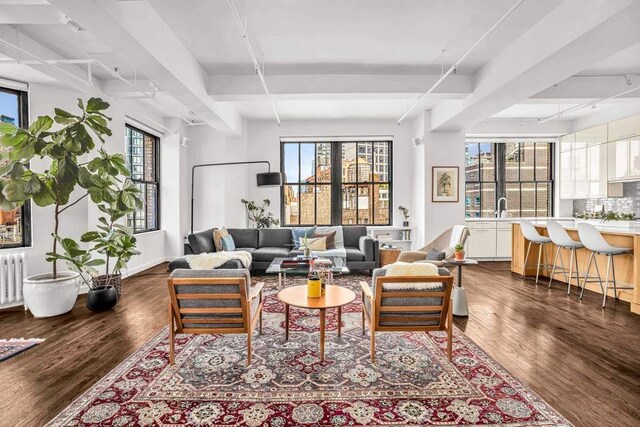 living room with radiator, beamed ceiling, and wood finished floors