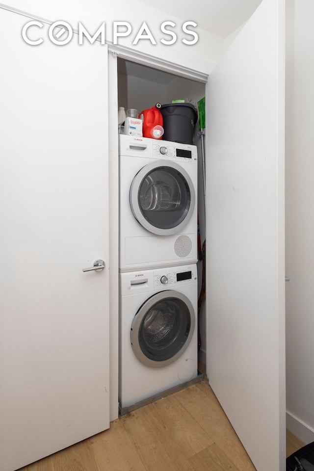 washroom with light wood finished floors, laundry area, and stacked washer and dryer