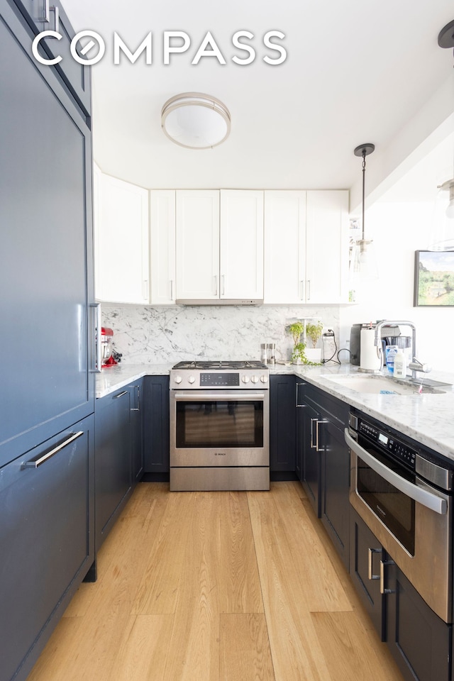 kitchen with white cabinets, light stone counters, gas stove, and light wood finished floors