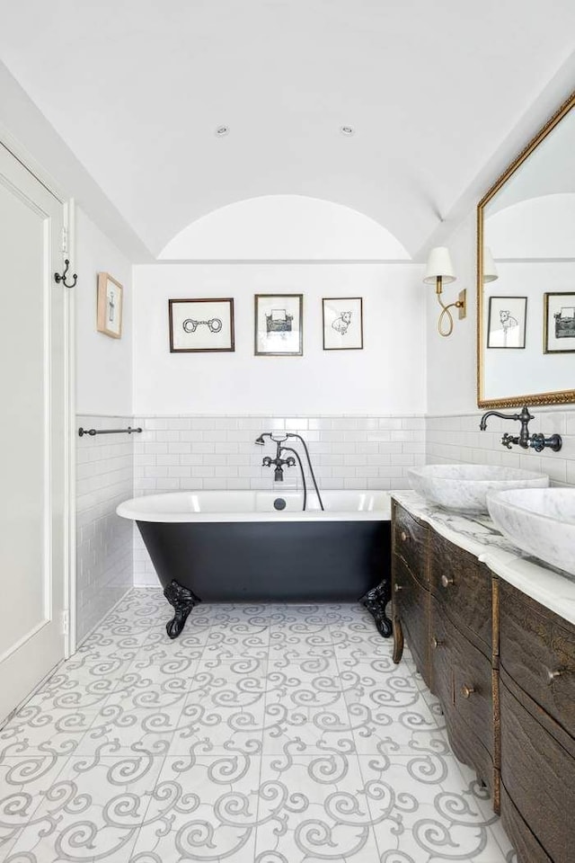 bathroom with a freestanding bath, tile walls, a wainscoted wall, and vanity