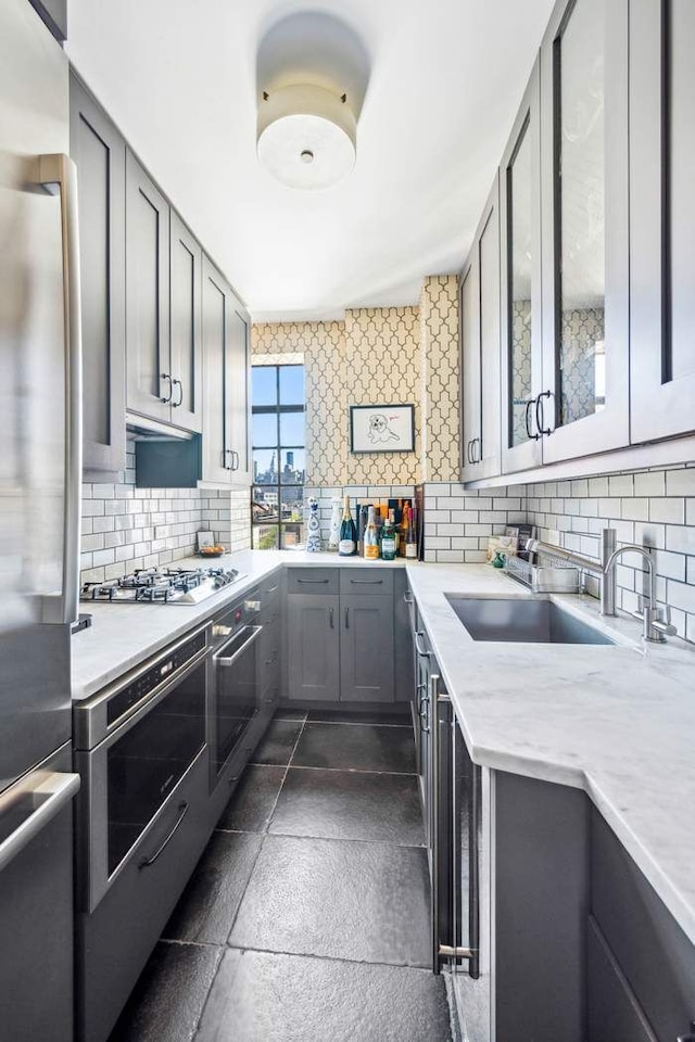 kitchen featuring a sink, appliances with stainless steel finishes, backsplash, and light countertops