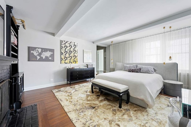 bedroom featuring baseboards, wood finished floors, and beamed ceiling