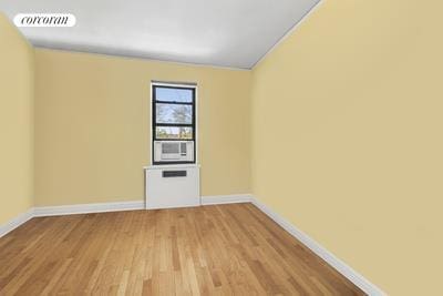 empty room with visible vents, wood finished floors, baseboards, cooling unit, and vaulted ceiling