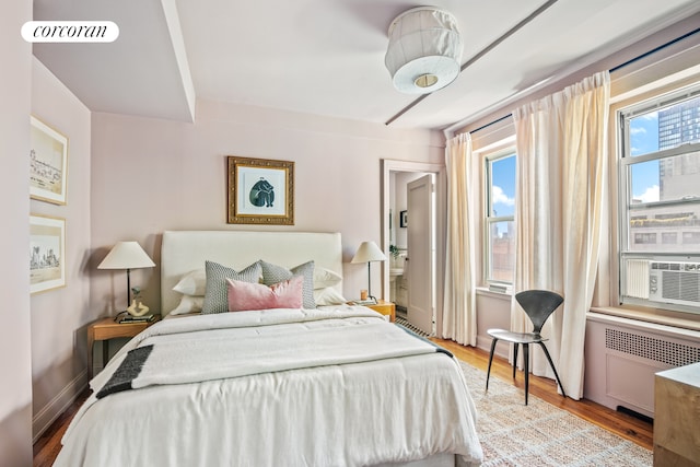 bedroom with radiator, baseboards, light wood finished floors, and visible vents