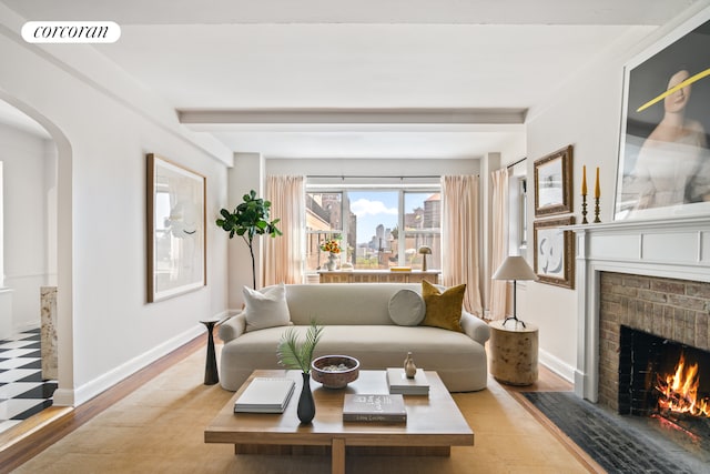 living area featuring visible vents, wood finished floors, a fireplace, baseboards, and arched walkways