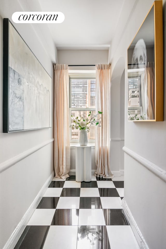 hallway with arched walkways and tile patterned floors