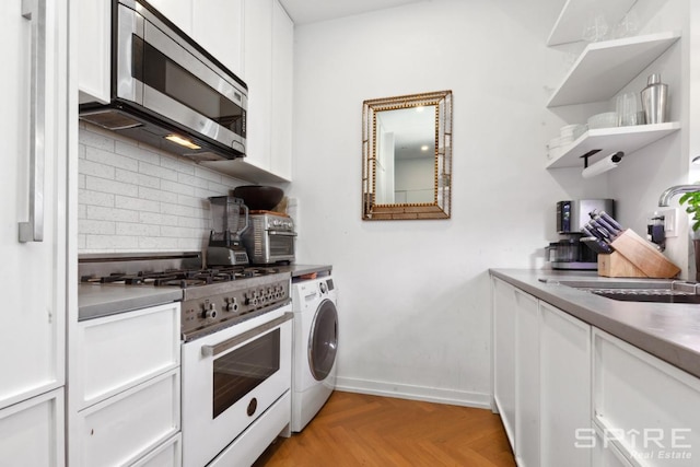 kitchen featuring decorative backsplash, gas range gas stove, stainless steel microwave, washer / dryer, and white cabinetry