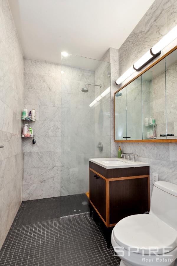 full bathroom with a walk in shower, vanity, toilet, tile patterned floors, and tile walls