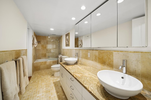 bathroom featuring toilet, tile patterned floors, tile walls, and a sink