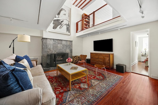 living room featuring track lighting, baseboards, wood finished floors, and a tile fireplace