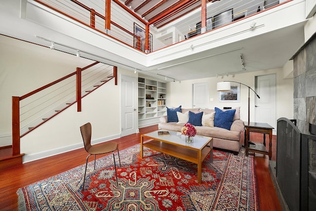 living area with stairway, baseboards, rail lighting, and wood finished floors