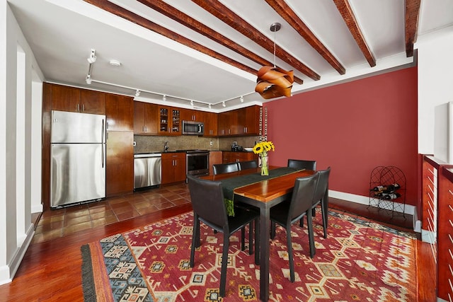 dining space with dark wood-style flooring, baseboards, and track lighting