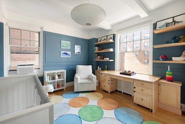 bedroom with light wood finished floors, beam ceiling, and cooling unit