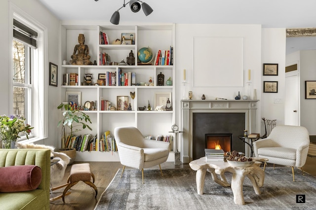 living area with a lit fireplace and wood finished floors