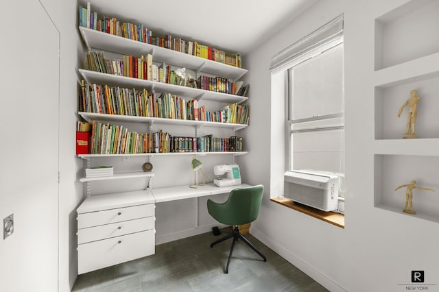 office area featuring baseboards, built in shelves, wood finished floors, and built in study area