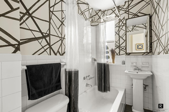 bathroom featuring shower / bath combo with shower curtain, toilet, tile walls, and a sink