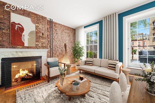 living area featuring crown molding, a fireplace, and brick wall