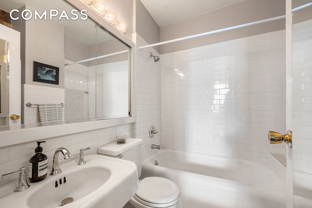 bathroom featuring a sink, toilet, tile walls, bathing tub / shower combination, and tasteful backsplash