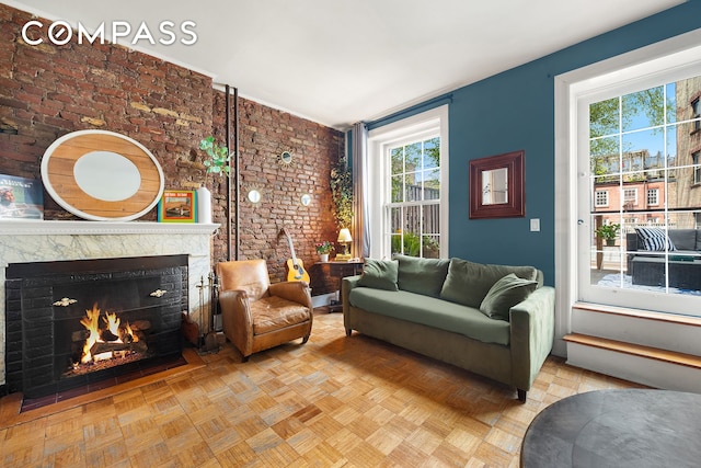 living area with a baseboard heating unit, brick wall, and a premium fireplace