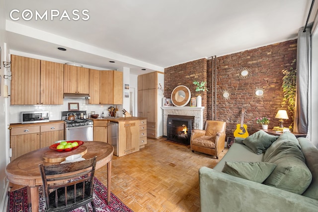 living area with brick wall and a large fireplace