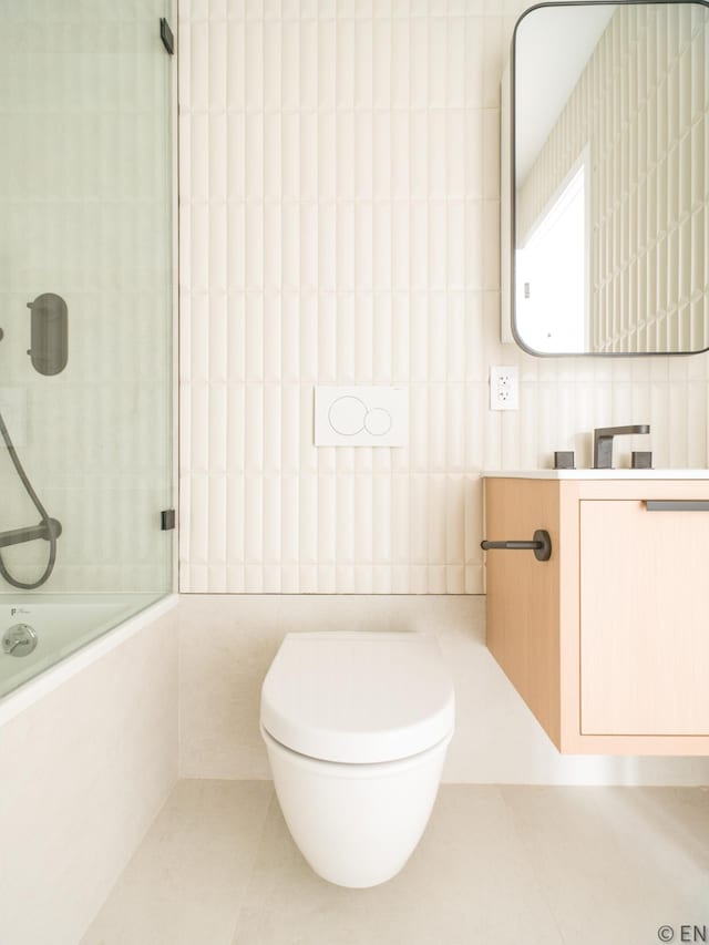 bathroom featuring tile walls, tile patterned flooring, vanity, tiled shower / bath, and toilet