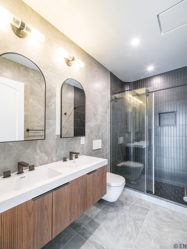 full bath with marble finish floor, toilet, tile walls, a sink, and a stall shower